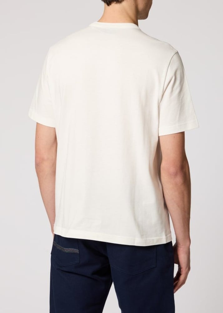A man viewed from the back wearing a plain off-white short-sleeve crewneck t-shirt and dark navy pants, against a light gray studio background.