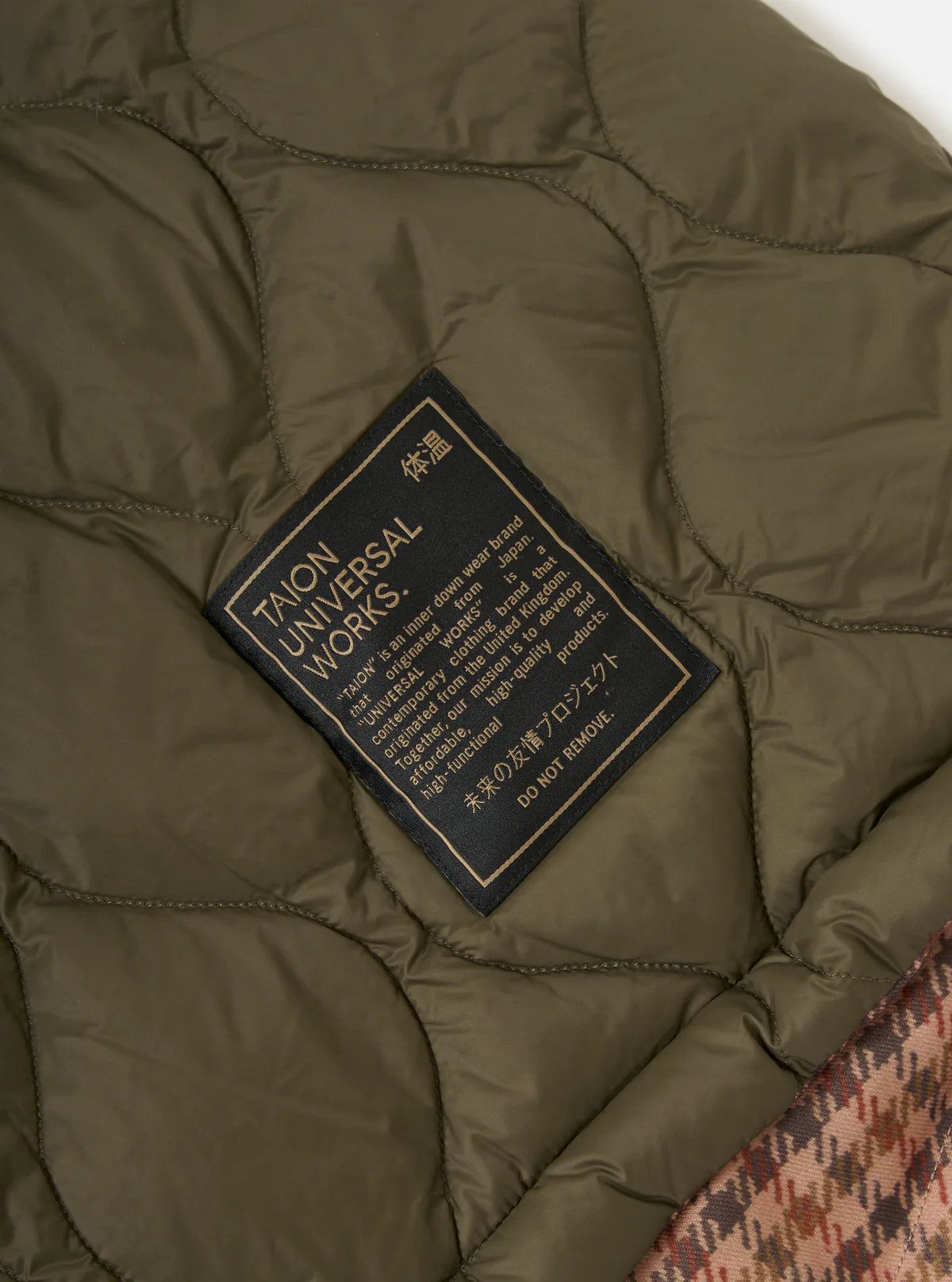 Close-up of a green puffer jacket with a brand label on a textured surface. #05AA3D