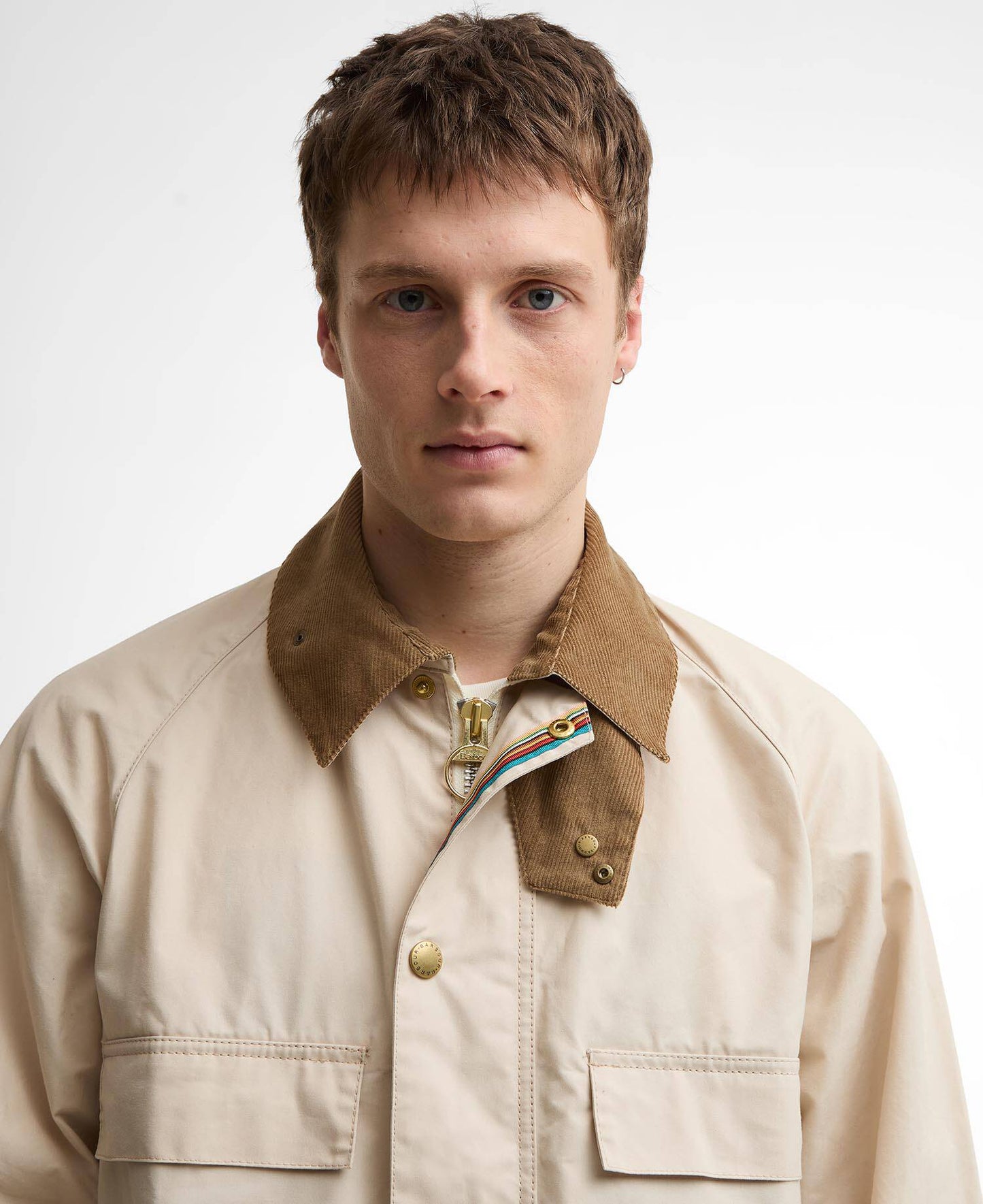Man wearing a beige jacket with a brown collar on a white background