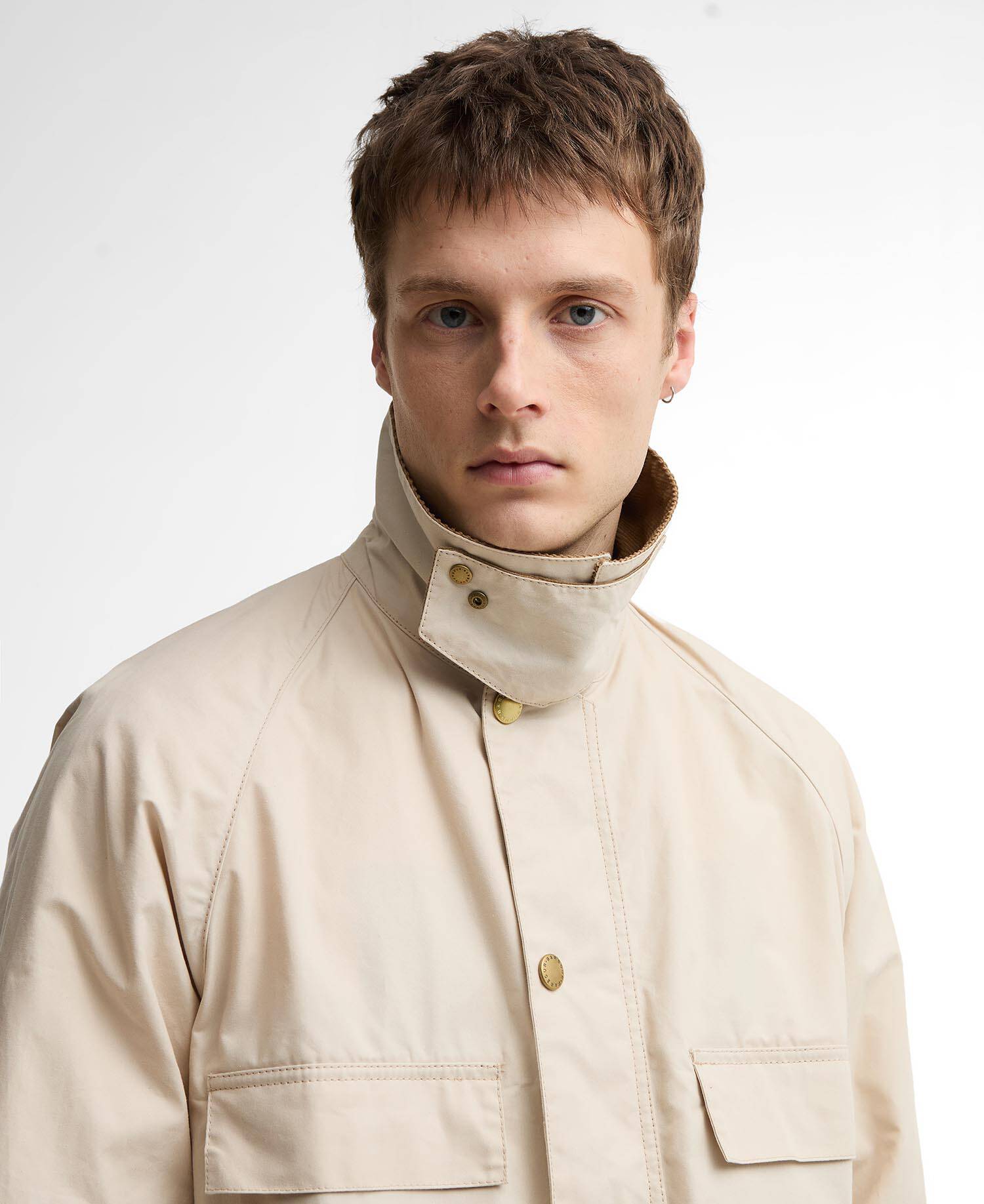 Man wearing a beige jacket with a high collar on a white background