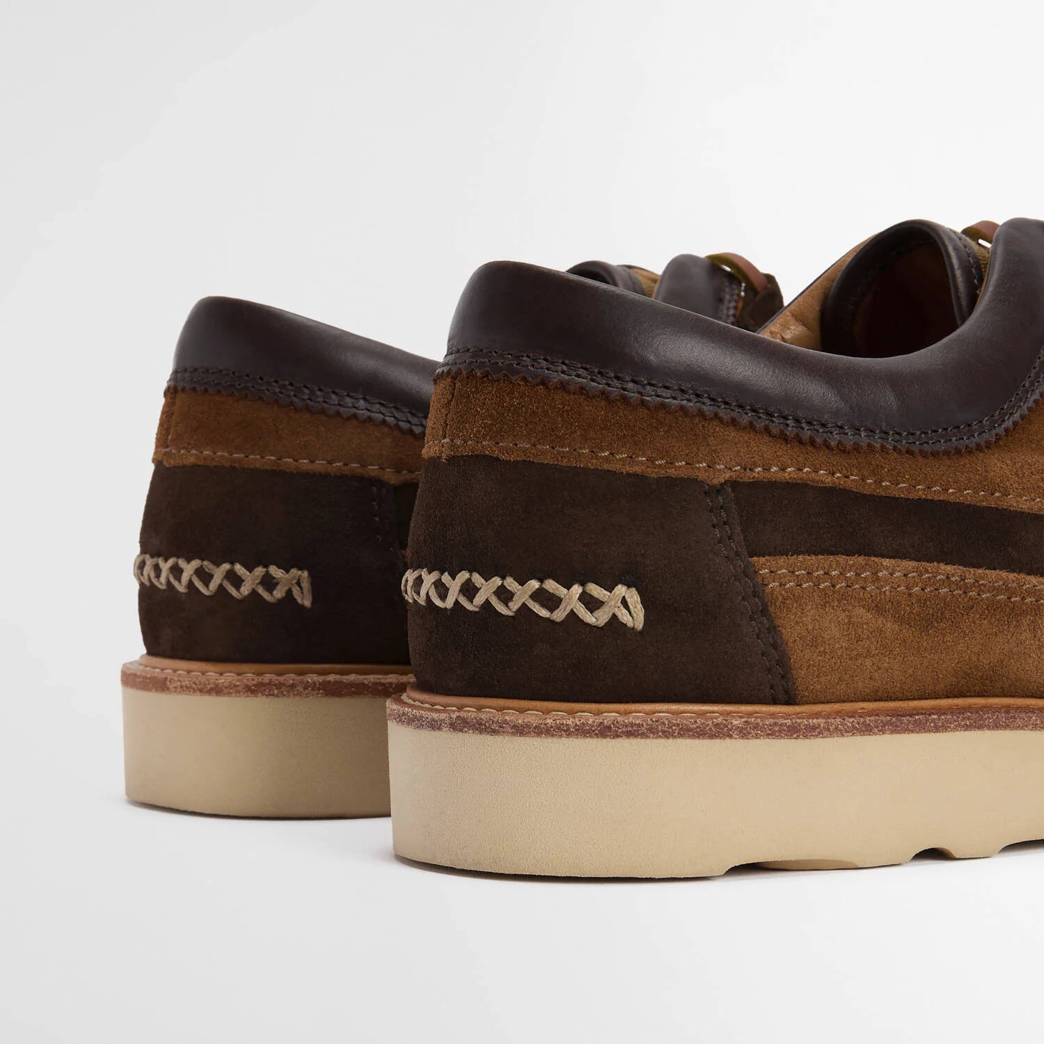 Brown suede shoes with white sole on a light gray background