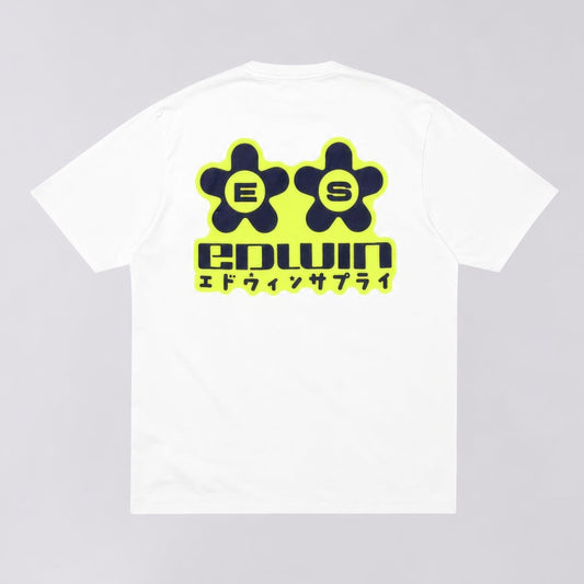 A white short-sleeve t-shirt with a large graphic on the back. The graphic features two dark green flower-like shapes with the letters 'E' and 'S' inside, outlined in neon yellow, above the word 'edwin' in dark green with a neon yellow outline, and Japanese katakana text underneath.